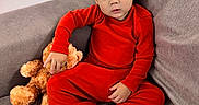 Jerome joined the competition — help win amazing prizes! barefoot, black_hair, casual, child, couch, cozy, curious_expression, cute, home, indoors, pajamas, plush_toy, portrait, red_clothing, relaxed, sitting, sofa, teddy_bear, toddler, young_child