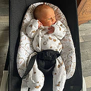 Marlon participe au concours pour gagner de l'argent avec cette photo : baby, newborn, infant, bouncer, baby_bouncer, baby_seat, onesie, patterned_clothing, harness, buckle, soft_cushion, wooden_floor, flooring, indoor, portrait, side_gaze, hand_near_face, legs, cozy, parenthood