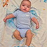 animal_print, arms, baby, blanket, blue_clothing, child, cute, face, indoors, infant, legs, light_blue, lying_down, playful, portrait, smiling, socks, soft_texture, stars, young_child