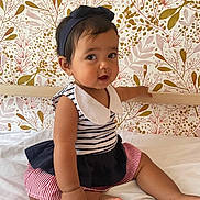 Calypso participe au concours pour gagner de l'argent avec cette photo : baby, child, infant, sitting, bed, striped_clothing, headband, curly_hair, cute, floral_wallpaper, white_bed, indoors, portrait, skin, barefoot, pink, navy_blue, red_stripes, collar, expression