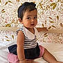 baby, child, infant, sitting, bed, striped_clothing, headband, curly_hair, cute, floral_wallpaper, white_bed, indoors, portrait, skin, barefoot, pink, navy_blue, red_stripes, collar, expression