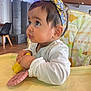 baby, child, infant, high_chair, headband, toy, indoor, curious, gaze, clothing, person, face, hand, table, seat, furniture, bright, colorful, cute, expression