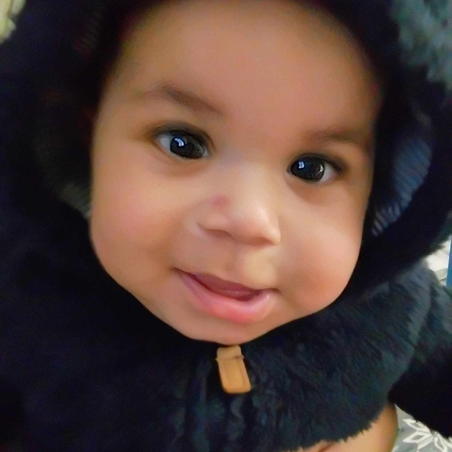 Sir' Hunter is registered to the contest to win money with this photo: apparel, baby, black_clothing, child, closeup, cozy, cute, eyes, face, fingers, hand, hood, indoor, infant, jacket, person, portrait, smile, warm, young