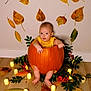 baby, pumpkin, yellow_clothing, autumn_leaves, candles, floor, wall, indoor, festive, fall, decoration, greenery, berries, cute, child, sitting, holiday, seasonal, orange, celebration