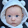Ethan is registered to the contest to win money with this photo: baby, child, hoodie, white_clothing, bear_ears, car_seat, seatbelt, face, blue_eyes, closeup, infant, cute, expression, serious, soft_texture, young_child, portrait, indoors, warm_clothing, looking_at_camera