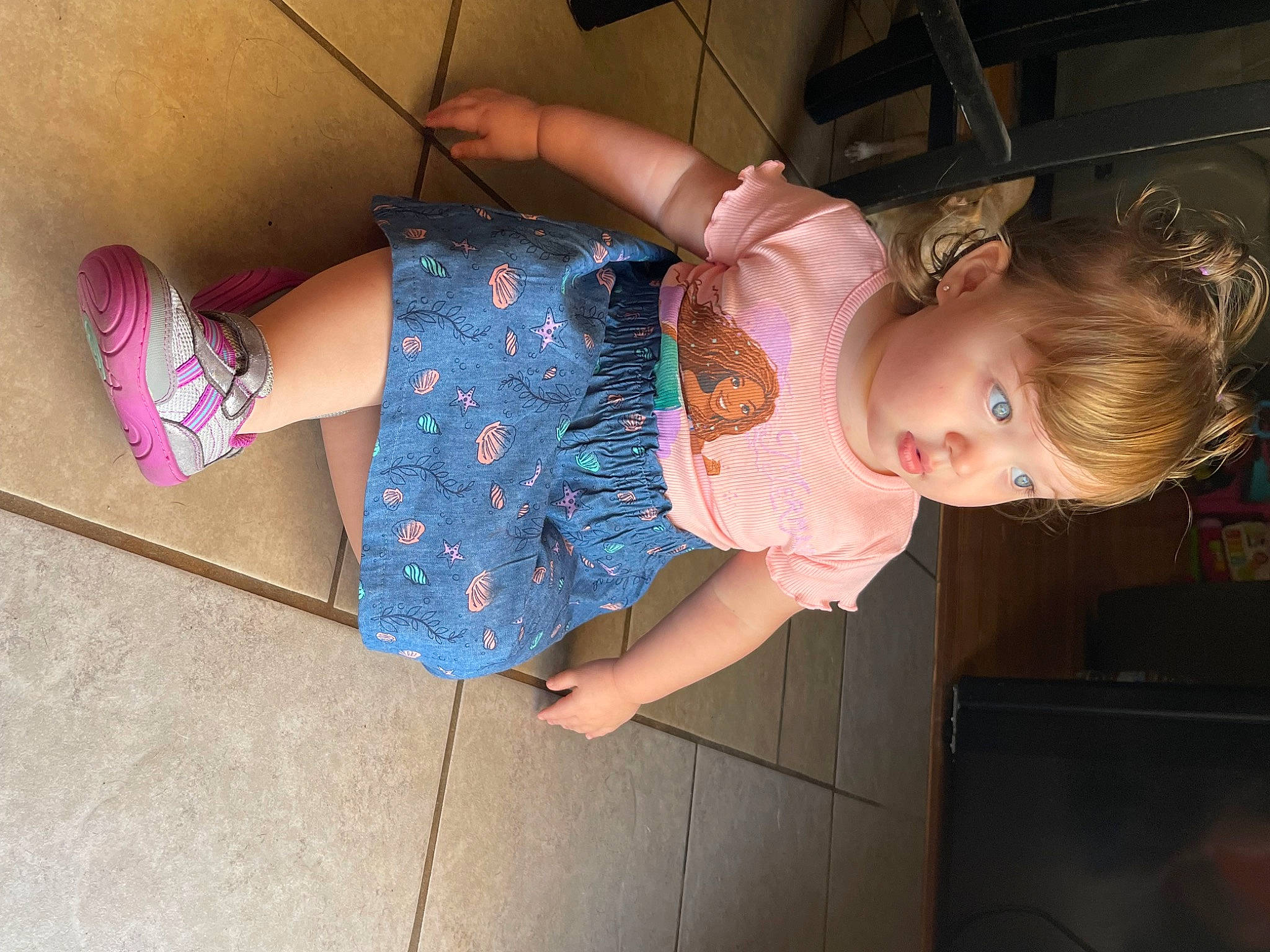 Sutton is registered to the contest to win money with this photo: arm, baby_toddler_clothing, cheek, dress, finger, flooring, foot, fun, glasses, hand, happy, human_body, human_leg, joint, knee, person, pink, skin, thigh, toddler