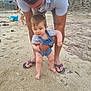 Diego participe au concours pour gagner de l'argent avec cette photo : baby, adult, beach, sand, child, playing, summer, footwear, denim_overalls, stone_wall, towel, outdoor, person, vacation, nature, family, casual_clothing, barefoot, support, exploration