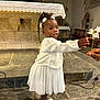child, girl, white_dress, flower, daisy, church, altar, stone_floor, indoor, person, shoes, curly_hair, hair_accessory, hand, offering, decoration, bench, window, religious, ceremony