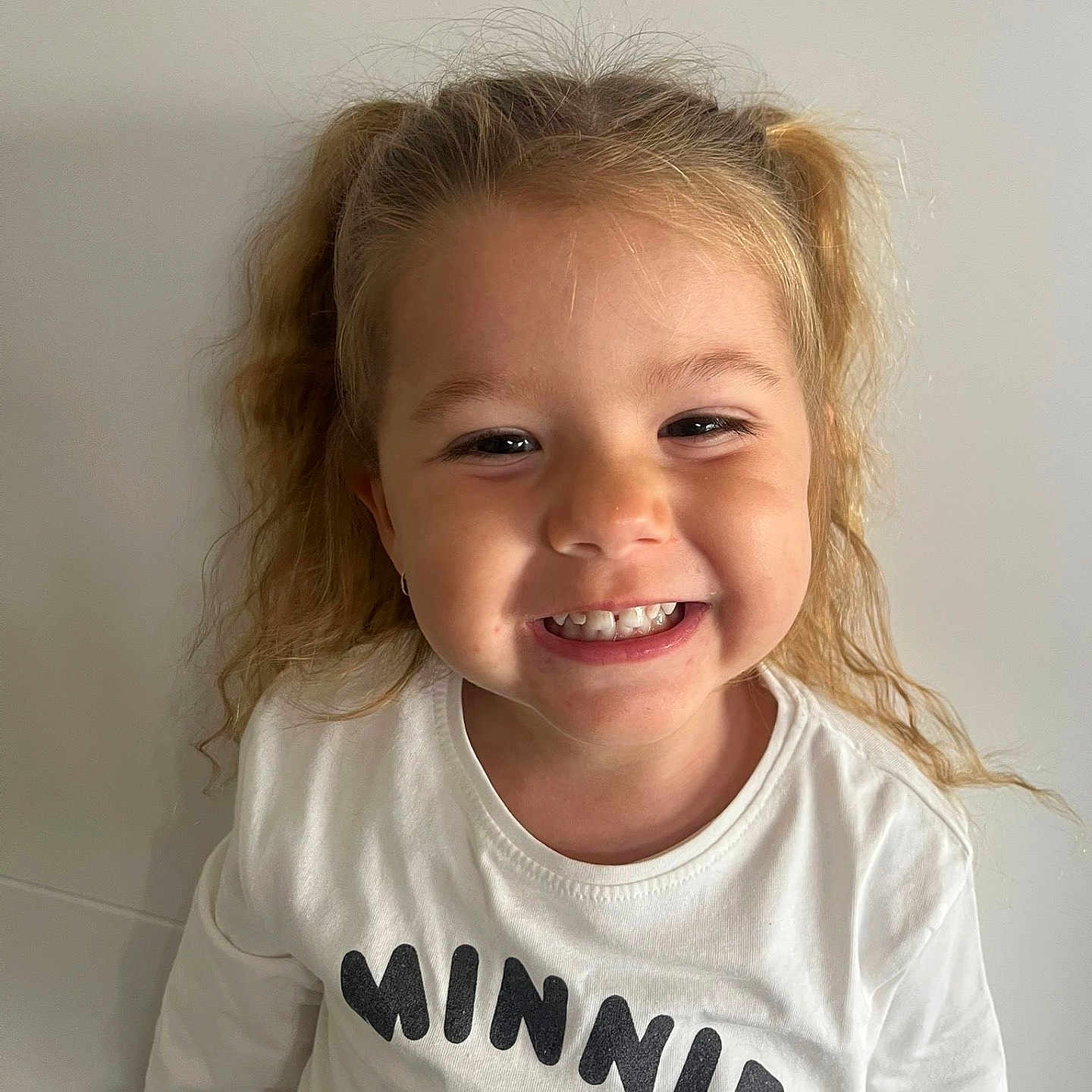 Joy participe au concours pour gagner de l'argent avec cette photo : casual_clothing, child, childhood, curly_hair, cute, face, girl, happy, indoor, light_background, long_sleeves, minnie_mouse, person, pigtails, playful, portrait, smiling, teeth, white_shirt, young
