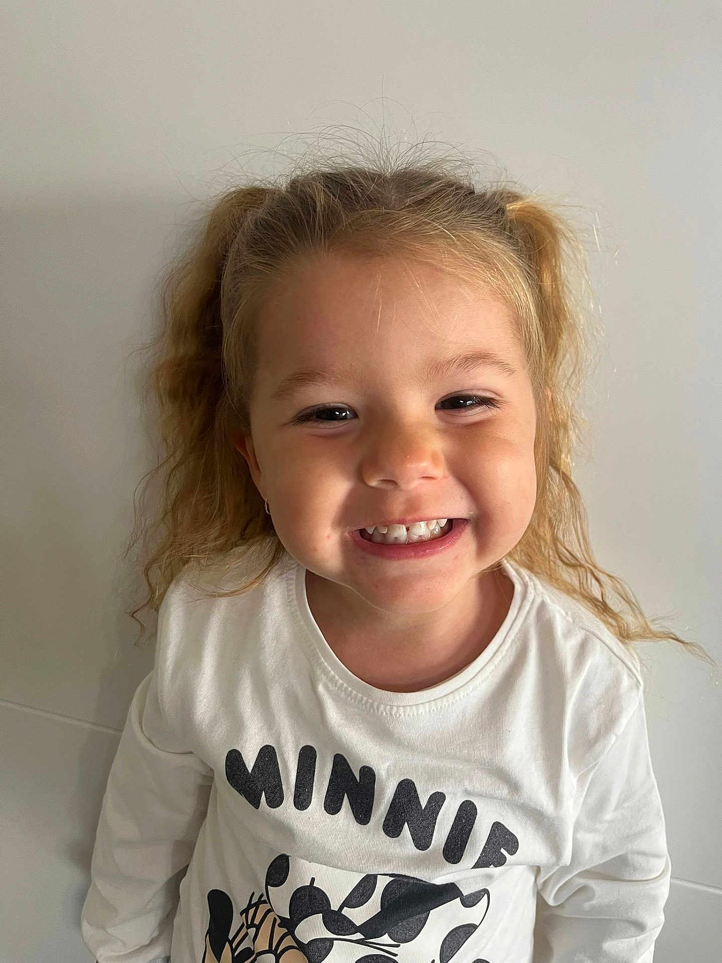 Joy participe au concours pour gagner de l'argent avec cette photo : child, girl, smiling, pigtails, curly_hair, white_shirt, minnie_mouse, portrait, happy, cute, young, casual_clothing, indoor, light_background, person, face, teeth, long_sleeves, childhood, playful