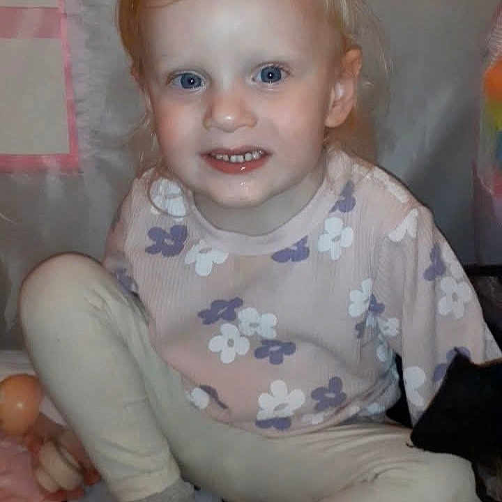 Ada-Rose is registered to the contest to win money with this photo: blanket, blonde_hair, blue_eyes, casual_clothing, child, cozy, cute, face, floral_sweater, happy, indoor, leggings, person, portrait, sitting, smiling, socks, toddler, toy, young_child