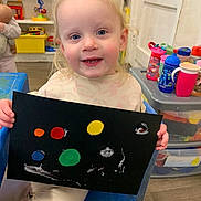 Ada-Rose joined the competition — help win amazing prizes! toddler, child, painting, art, colorful, black_paper, blue_chair, classroom, toys, cups, plastic_containers, smiling, happy, indoor, playroom, blonde_hair, person, creative, young_child, holding