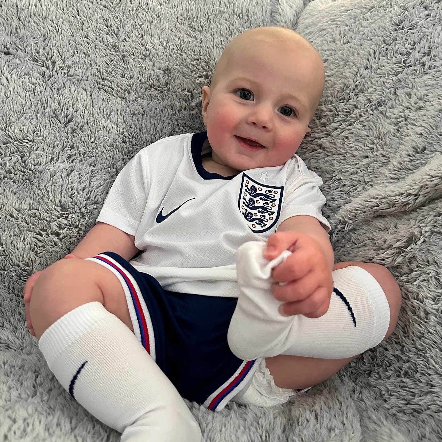 Bertie joined the competition — help win amazing prizes! baby, ball, bodypart, clothing, couch, face, finger, football, furniture, hand, head, homedecor, hosiery, person, photography, portrait, shorts, sitting, sock, t_shirt