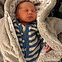 newborn, baby, sleeping, blanket, hood, striped_clothing, cozy, fur, cute, infant, soft, warm, peaceful, portrait, child, buttoned_clothing, hand, face, indoors, resting