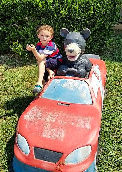 Kolby is registered to the contest to win money with this photo: automotive_design, automotive_exterior, automotive_lighting, bumper, car, grass, green, grille, headlamp, hood, leisure, motor_vehicle, person, personal_luxury_car, photograph, plant, recreation, red, vehicle, vehicle_door