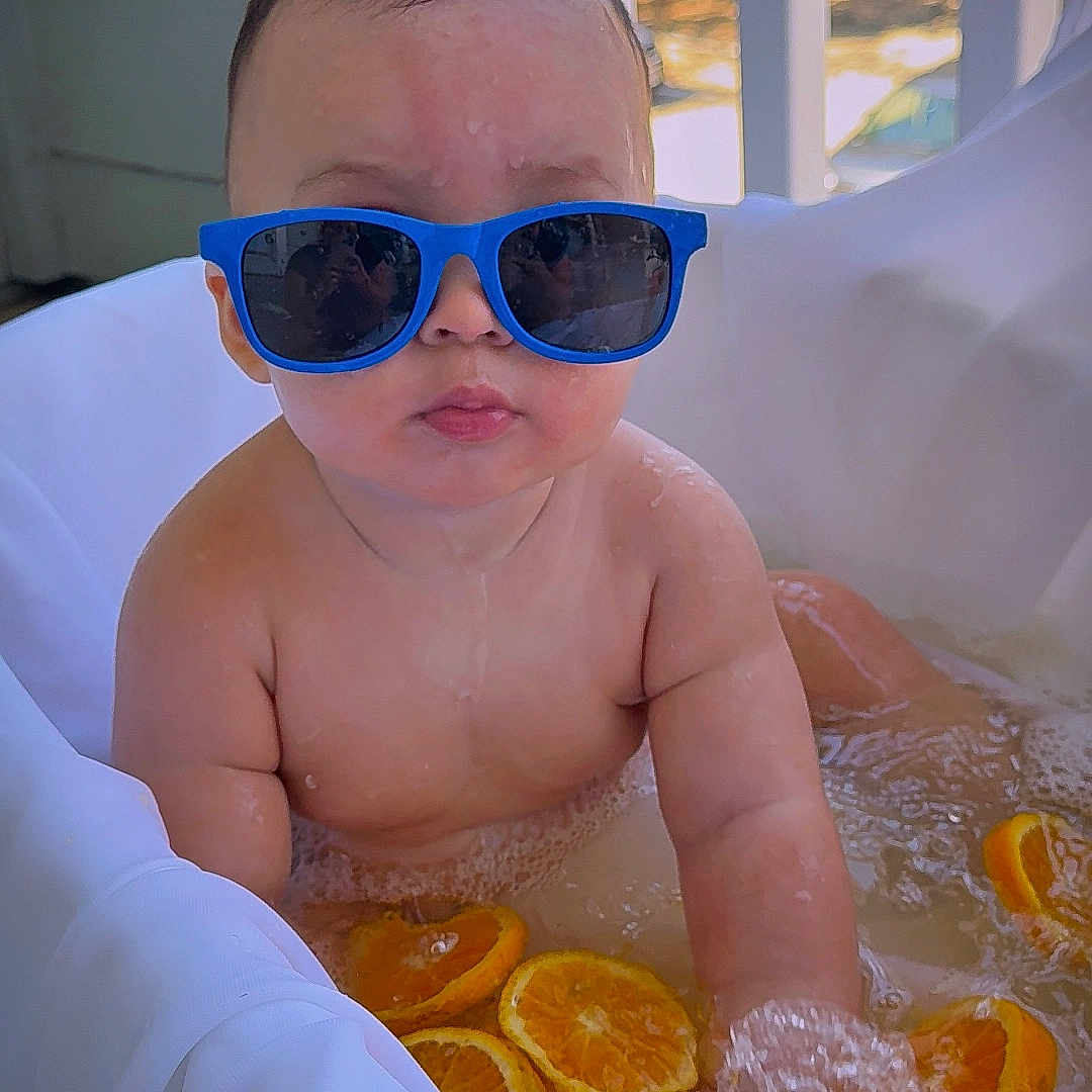 Kamil Izarra joined the competition — help win amazing prizes! baby, bath, bathtub, blue_sunglasses, child, citrus, close_up, funny, indoor, infant, orange_slices, poolside, portrait, relaxed, sitting, sunglasses, sunlight, water, wet, window