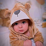 Kamil Izarra is registered to the contest to win money with this photo: baby, infant, child, portrait, close_up, smiling, wide_eyed, bear_costume, hood, plush, brown, outfit, hands, fists, indoor, bed, blanket, soft_lighting, adorable, photography