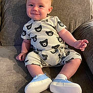 Weston is registered to the contest to win money with this photo: baby, child, smile, couch, clothing, bear_pattern, shoes, socks, indoor, furniture, happy, person, sitting, cute, infant, casual, young, portrait, cozy, relaxed