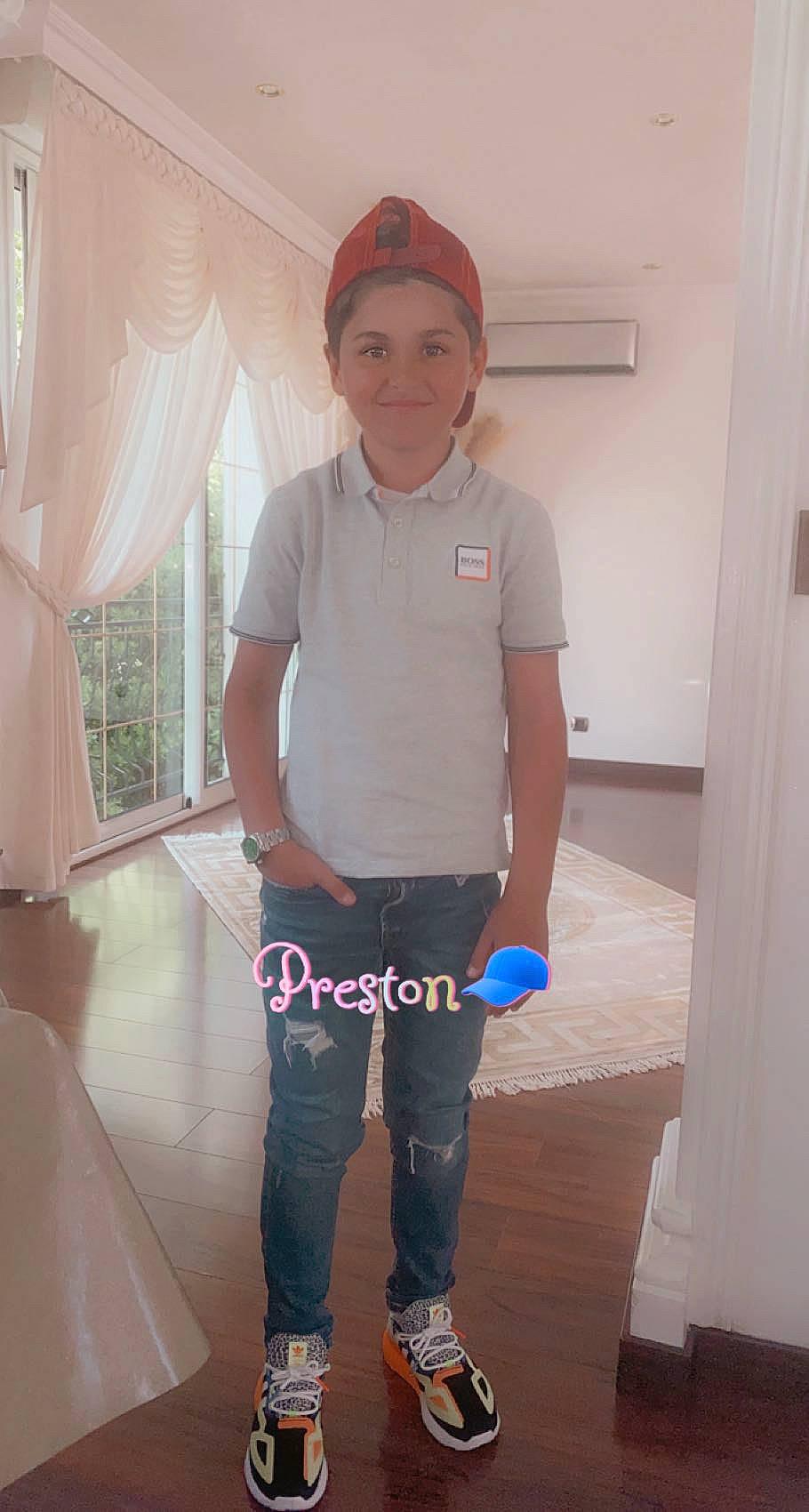 Preston participe au concours pour gagner de l'argent avec cette photo : baseball_cap, cap, curtain, denim, door, elbow, electric_blue, floor, flooring, hardwood, human_leg, joy, knee, material_property, person, sleeve, t_shirt, thigh, thumb, trunk