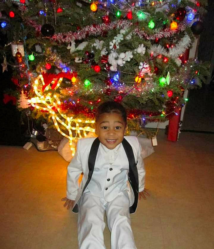 Maïlan a rejoint le concours — aidez-le/la à gagner de superbes lots ! black, christmas_ornament, christmas_tree, facial_expression, fun, green, happy, head, human_body, joy, light, mammal, martial_arts_uniform, person, plant, smile, sports_uniform, standing, toddler, tree