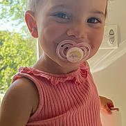 Layana participe au concours pour gagner de l'argent avec cette photo : toddler, child, pacifier, pink_top, smile, face, hair, window, sunlight, indoors, hand, light_switch, greenery, background, portrait, person, cute, happy, young_child, fashion