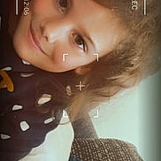 Layana a rejoint le concours — aidez-le/la à gagner de superbes lots ! 4k_label, camera_overlay, child, closeup, cozy, curly_hair, eyes, face, framing_marks, home, indoors, pillow, polka_dot_clothing, portrait, rec_marker, smile, sofa, timestamp, warm_lighting, young_person