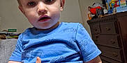 Sawyer is registered to the contest to win money with this photo: toddler, child, blue_shirt, indoor, person, furniture, dresser, clutter, toy_box, face, hand, light_hair, curious, casual, home, room, carpet, adult_hand, expression, portrait