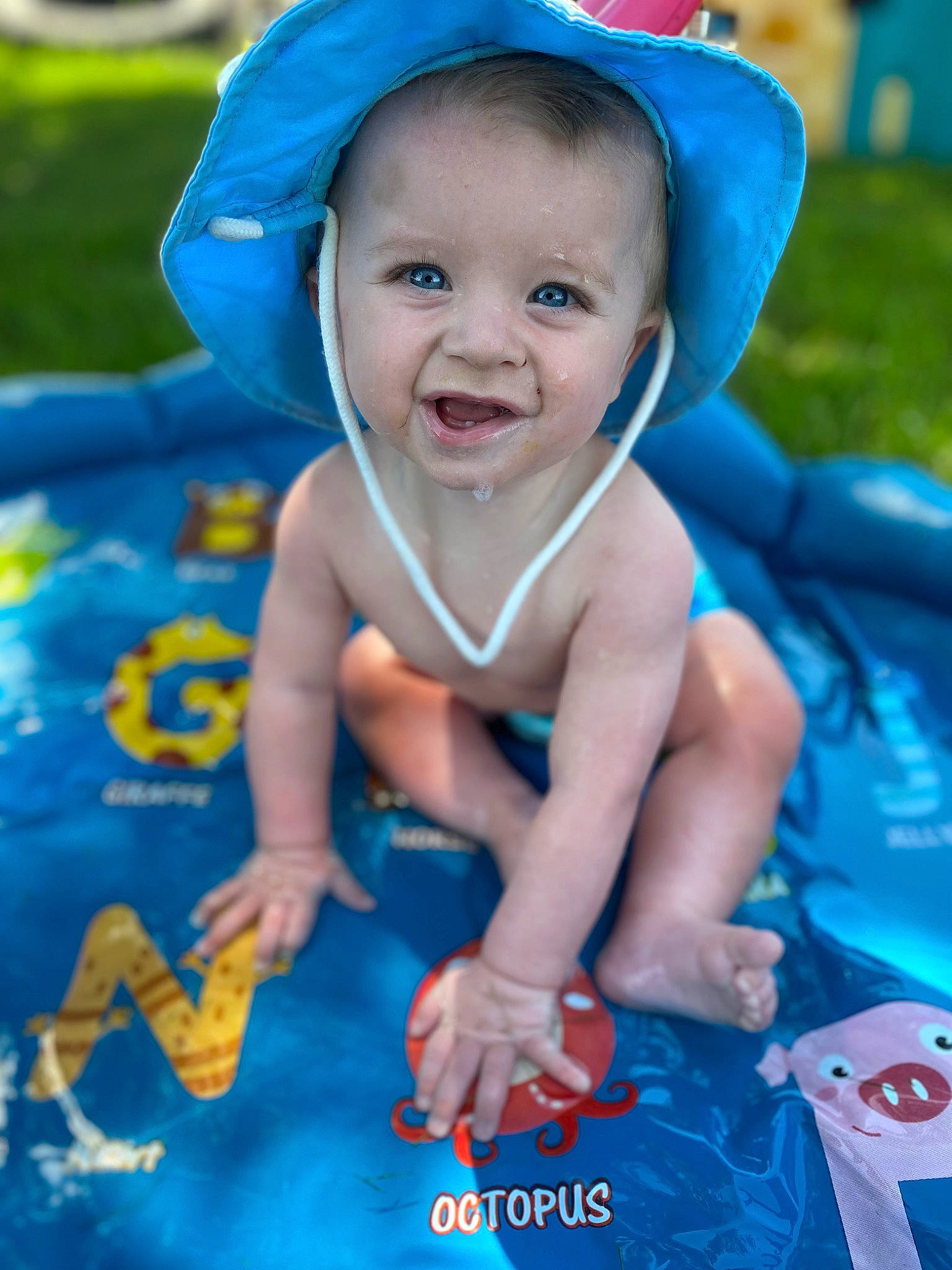 Donald is registered to the contest to win money with this photo: aqua, azure, baby, baby_toddler_clothing, blue, facial_expression, finger, fun, grass, happy, hat, leisure, person, photograph, pink, product, skin, smile, sun_hat, textile