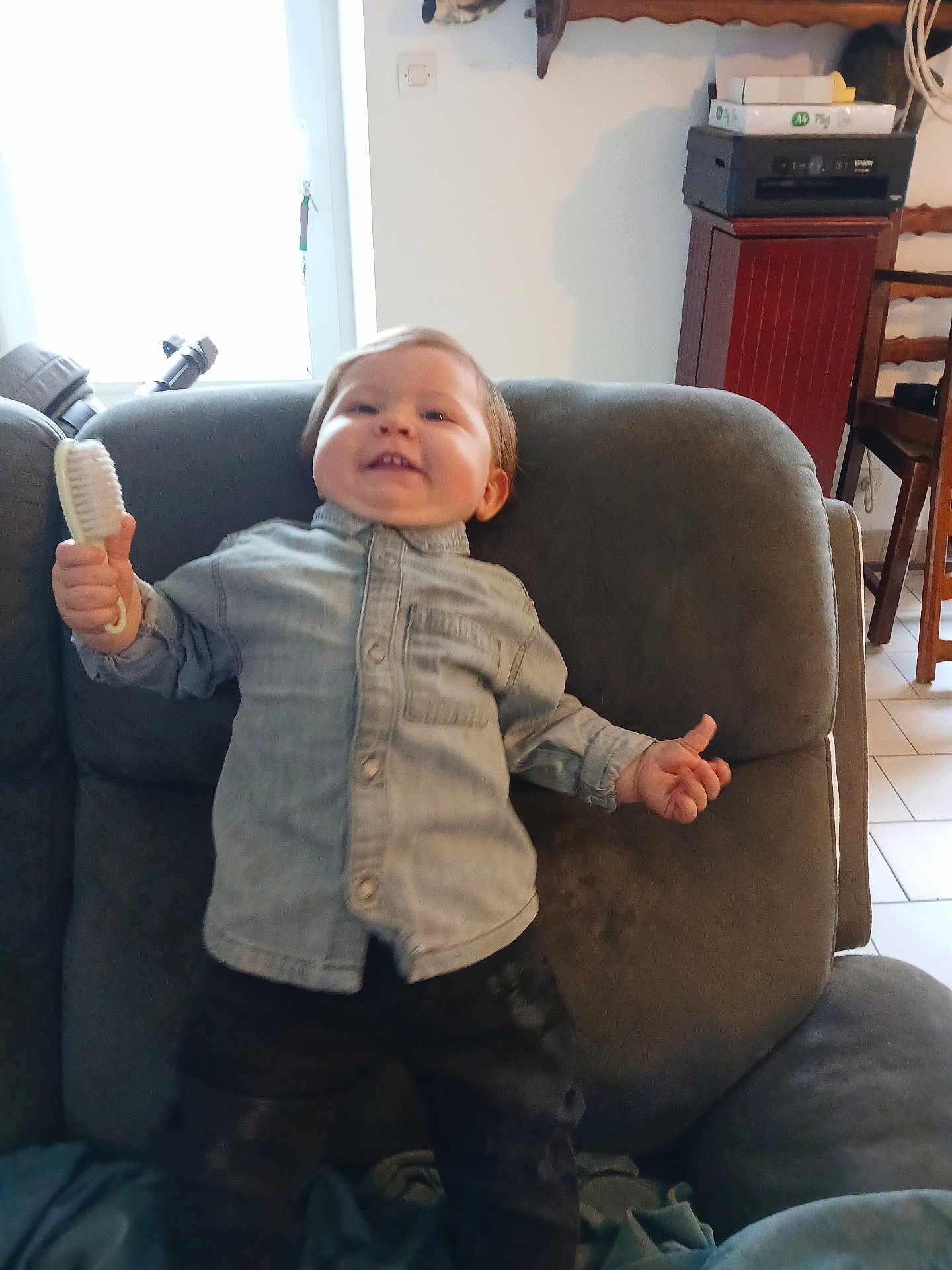 John a rejoint le concours — aidez-le/la à gagner de superbes lots ! child, toddler, smile, brush, armchair, couch, denim_shirt, button_up, happy, indoor, living_room, furniture, portrait, hair, tooth, playful, blanket, tile_floor, printer, chair