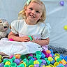 child, girl, smile, easter_eggs, colorful, plastic_eggs, plush_toy, bunny, white_dress, hair_bow, happy, indoor, soft_rug, toy, cute, festive, celebration, baby, portrait, playful