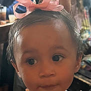 Selena is registered to the contest to win money with this photo: toddler, child, face, bow, hair, pink, ribbon, closeup, portrait, skin, expression, indoors, person, young, cute, innocent, clothing, shoulders, headwear, curious