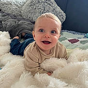 Gabriel a rejoint le concours — aidez-le/la à gagner de superbes lots ! baby, child, smiling, blue_eyes, blanket, couch, pillow, indoor, happy, cozy, soft_texture, casual_clothing, infant, portrait, home, cute, young_child, relaxing, comfort, playful