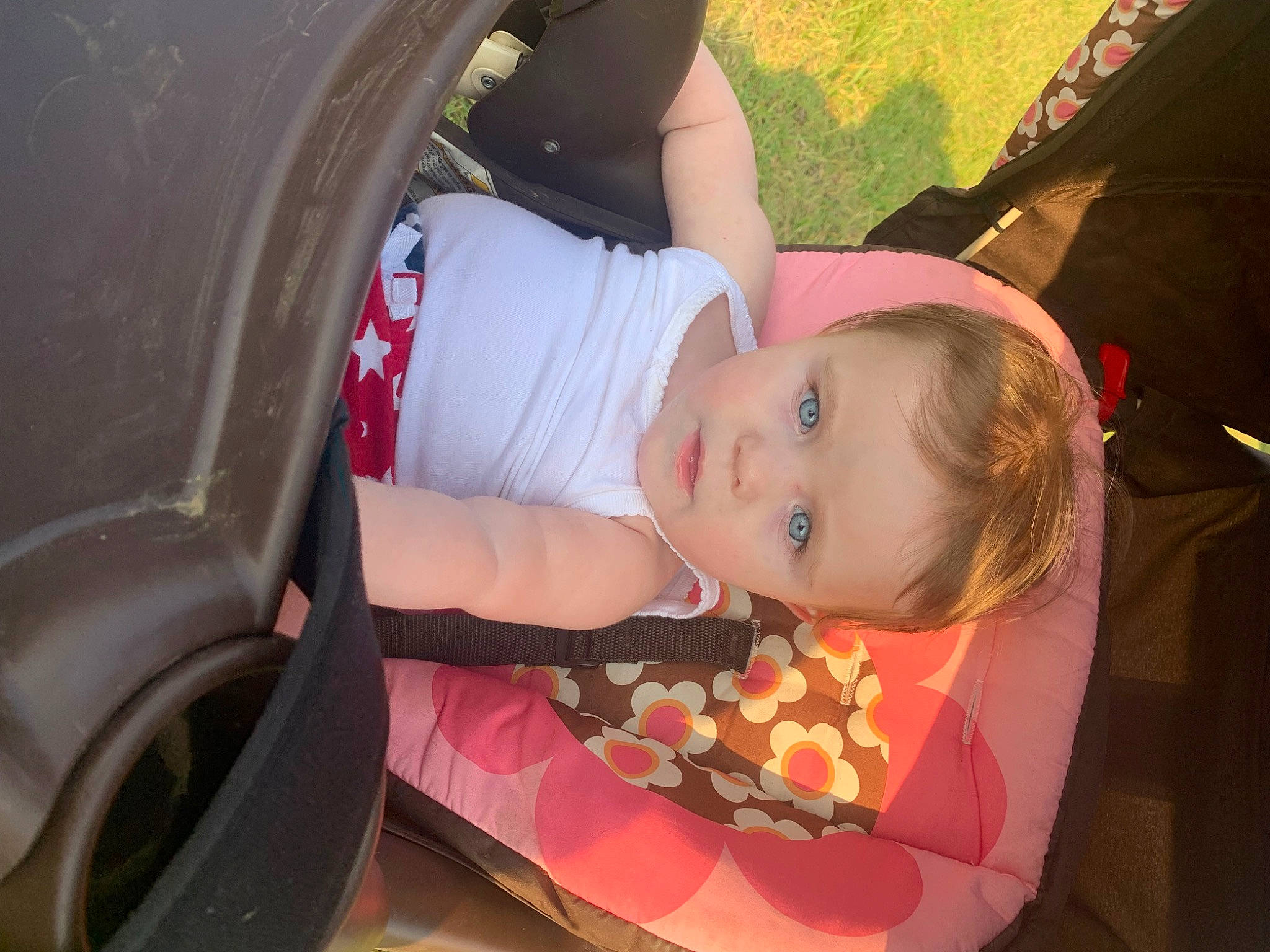 Zoey is registered to the contest to win money with this photo: automotive_lighting, automotive_tire, baby, baby_carriage, car, dress, fender, fun, grass, happy, hat, orange, person, pink, plant, tire, toddler, tree, vehicle_door, wheel