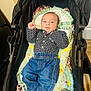 baby, stroller, blanket, jeans, shirt, infant, child, smartphone, footwear, socks, indoor, wooden_floor, person, clothing, baby_clothes, patterned_clothing, lying_down, comfort, casual, calm