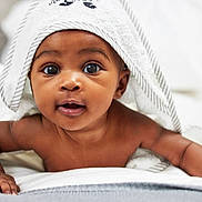 Emerie joined the competition — help win amazing prizes! baby, towel, child, infant, face, eyes, skin, hands, bed, blanket, expression, cute, portrait, lying_down, curious, indoors, soft, comfortable, young, person