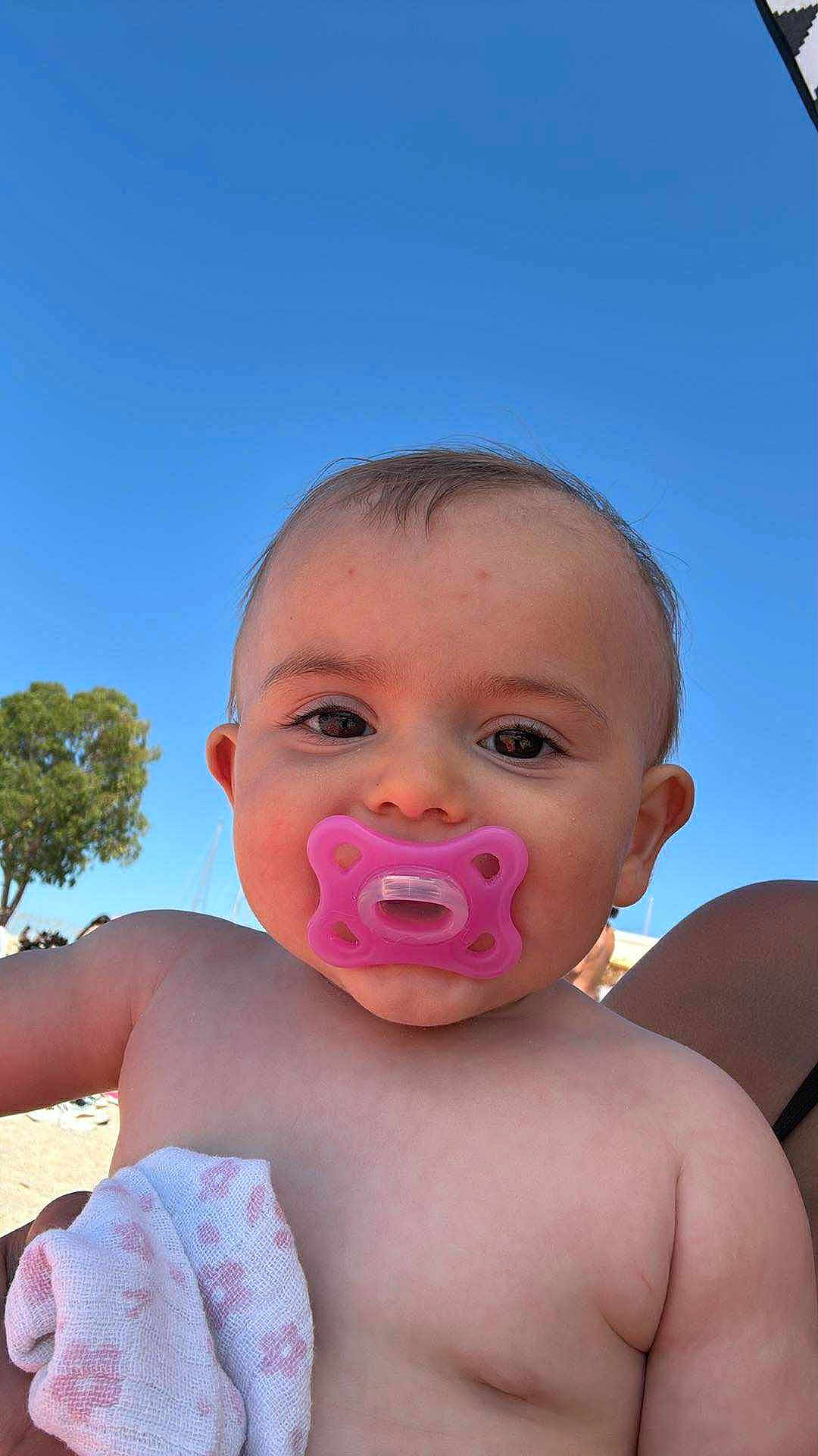 Louise a rejoint le concours — aidez-le/la à gagner de superbes lots ! baby, pacifier, child, infant, skin, cloth, outdoor, blue_sky, tree, face, portrait, cute, holding, summer, daylight, cheeks, bare_chest, expression, young, nature