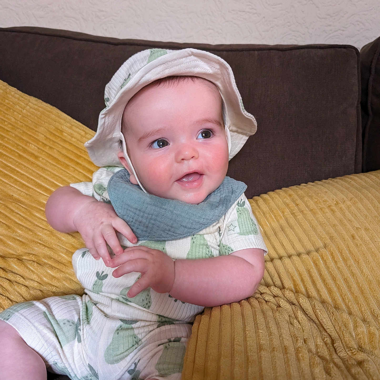 Teddy is registered to the contest to win money with this photo: baby, bodypart, bonnet, cap, clothing, couch, cushion, face, finger, furniture, hand, hat, head, homedecor, pants, person, photography, portrait, sitting, sunhat