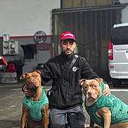 Blue participe au concours pour gagner de l'argent avec cette photo : man, dog, indoor, kneeling, green_sweater, brown_dog, tan_dog, pet, animal, garage, van, casual_clothing, cap, beard, floor, equipment, calm, portrait, companionship, matching_outfits