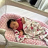 baby, sleeping, blanket, bassinet, pink, heart_pattern, mesh, cozy, indoor, child, resting, infant, soft, comfort, cushion, clothing, peaceful, nursery, fabric, toddler