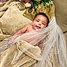 Kehlani is registered to the contest to win money with this photo: baby, blanket, veil, flower_bouquet, couch, soft_texture, smile, infant, portrait, indoors, cute, resting, decor, colorful_flowers, skin, curly_hair, closeup, happy, tulle, relaxing