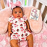 Kehlani is registered to the contest to win money with this photo: baby, infant, crib, pink, headband, bow, milestone_card, cushion, blanket, cherry_pattern, clothing, cute, child, portrait, indoors, resting, soft_toys, smiling, decor, person