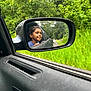 Kaison is registered to the contest to win money with this photo: child, car, side_mirror, reflection, window, greenery, trees, road, outdoor, vehicle, happy, smiling, nature, travel, portrait, boy, casual, daytime, scenery, leisure
