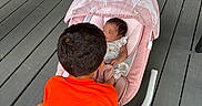 Kaison joined the competition — help win amazing prizes! child, baby, baby_rocker, porch, wooden_floor, broom, welcome_mat, door, sneakers, orange_shirt, sleeping_baby, pink_rocker, mesh_cover, toddler, shorts, outdoor, floor, person, infant, shoes