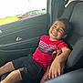 child, boy, smiling, car, car_seat, red_shirt, black_shorts, seatbelt, window, daylight, happy, casual, portrait, interior, relaxed, young, person, vehicle, sunlight, seat