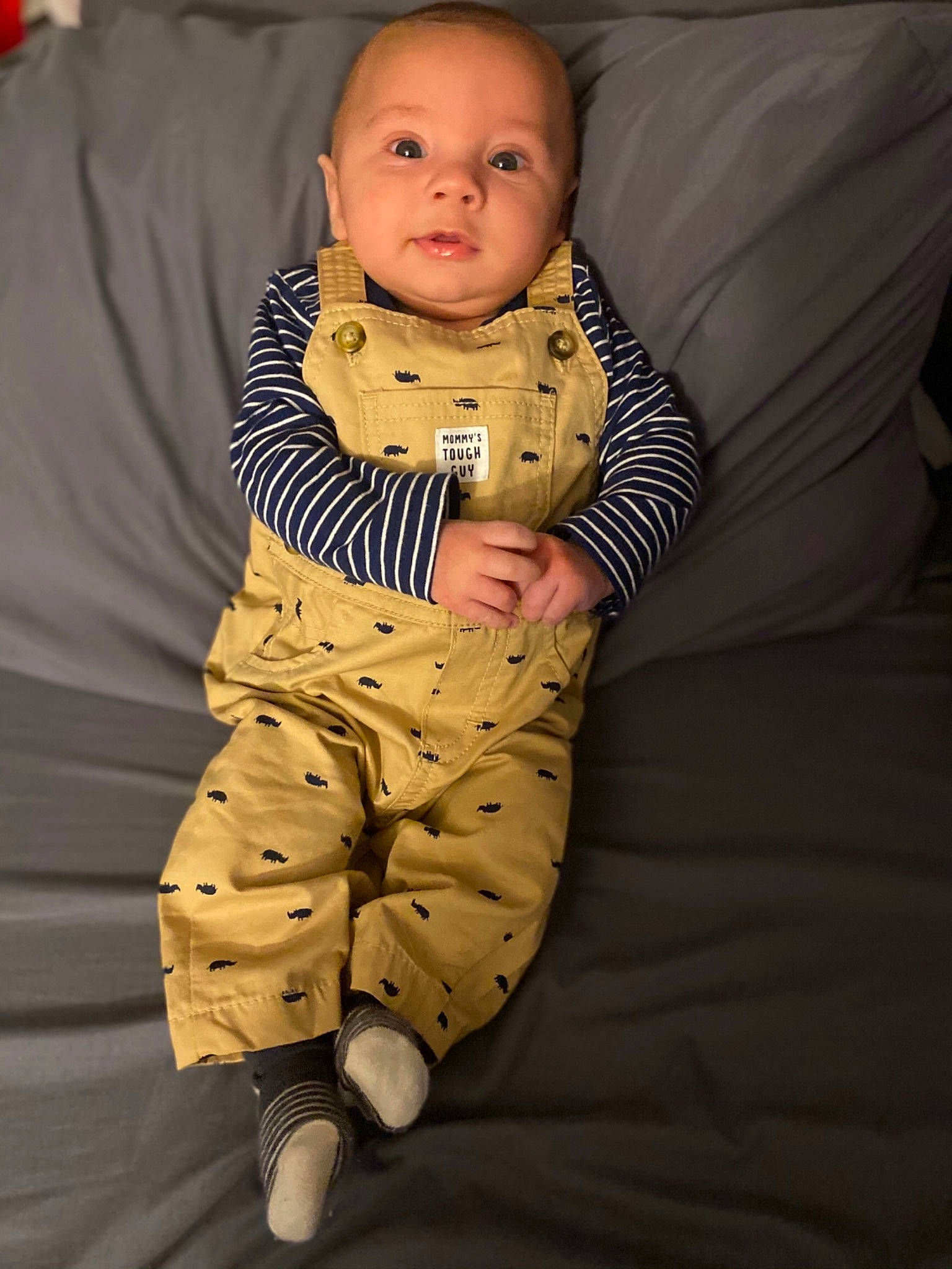 Johnny is registered to the contest to win money with this photo: abdomen, arm, baby, baby_toddler_clothing, cheek, child, comfort, elbow, eye, face, gesture, happy, head, linens, person, room, sitting, sleeve, smile, stomach