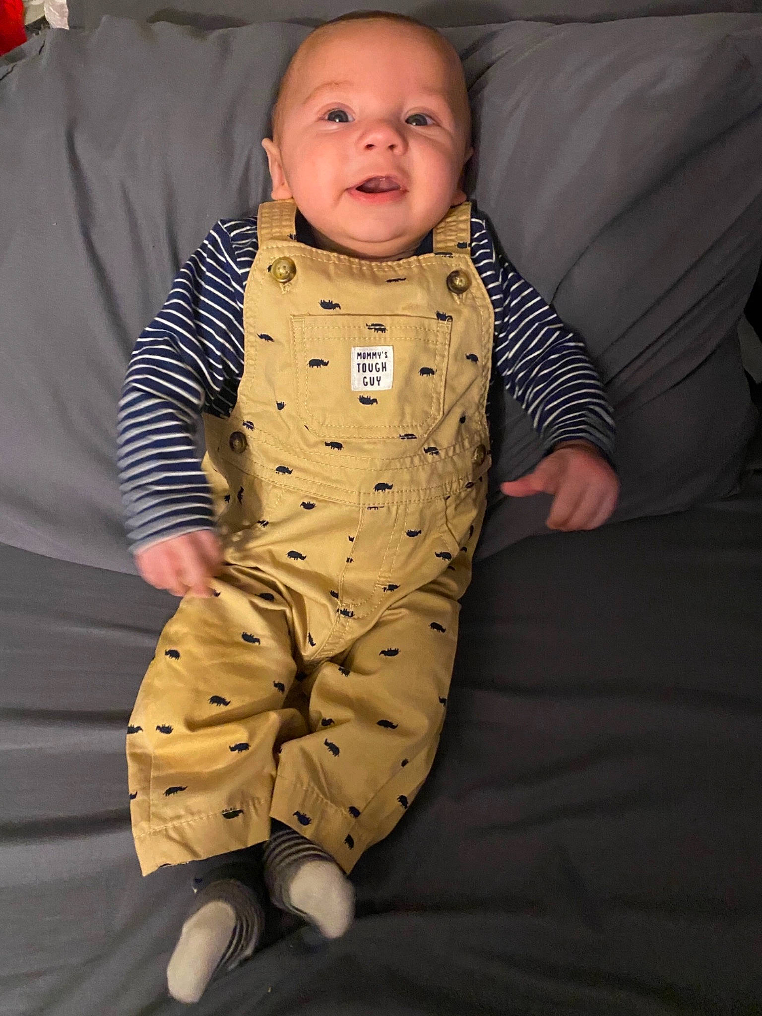 Johnny is registered to the contest to win money with this photo: baby, baby_toddler_clothing, bedding, cheek, child, chin, collar, comfort, eye, face, head, linens, nose, pattern, person, room, sitting, skin, sleeve, smile
