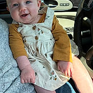 Harper joined the competition — help win amazing prizes! baby, infant, smiling, headband, yellow_bow, floral_dress, pinafore, car_interior, steering_wheel, door_handle, hand, legs, cheeks, blue_eyes, cozy, sunlight, lap, sweater, denim, portrait