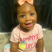 Na Laniyah is registered to the contest to win money with this photo: baby, child, smiling, pink_bow, cute, sitting, carpet, indoor, happy, toddler, clothing, face, person, portrait, bright_eyes, infant, cute_outfit, young_child, playful, adorable