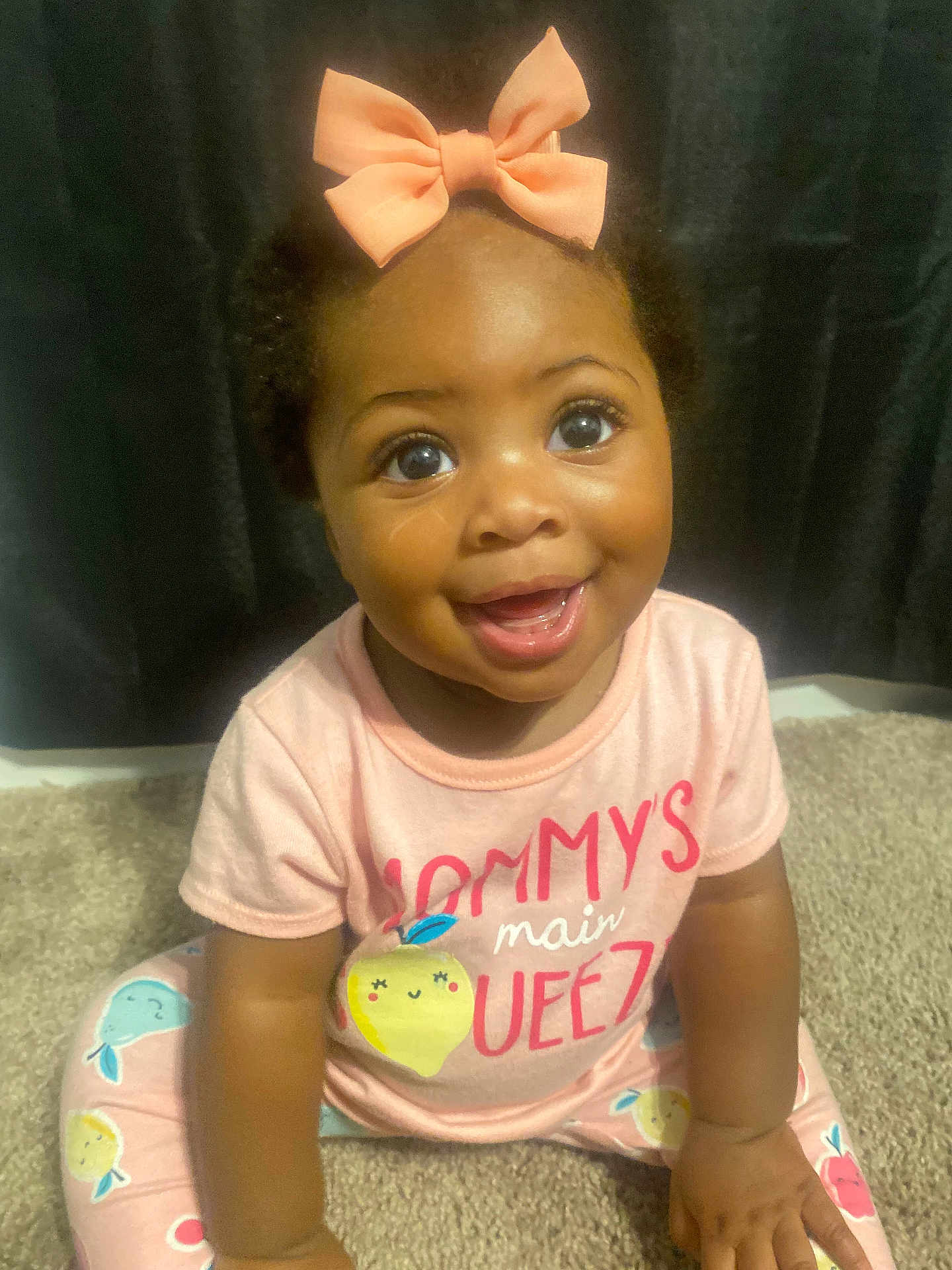 Na Laniyah is registered to the contest to win money with this photo: baby, child, smiling, pink_bow, cute, sitting, carpet, indoor, happy, toddler, clothing, face, person, portrait, bright_eyes, infant, cute_outfit, young_child, playful, adorable