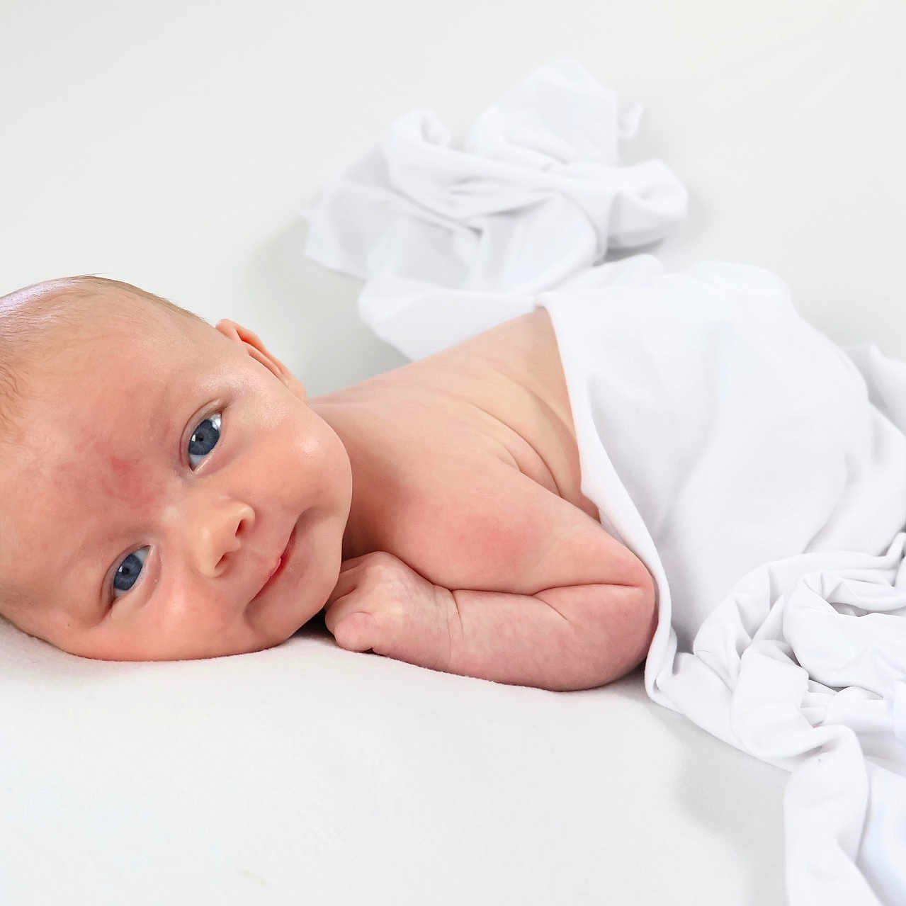 Giorgio joined the competition — help win amazing prizes! arm, baby, blanket, blue_eyes, child, curious, cute, face, head, indoors, infant, lying_down, minimalistic, newborn, portrait, resting, skin, smiling, soft_surface, white_cloth